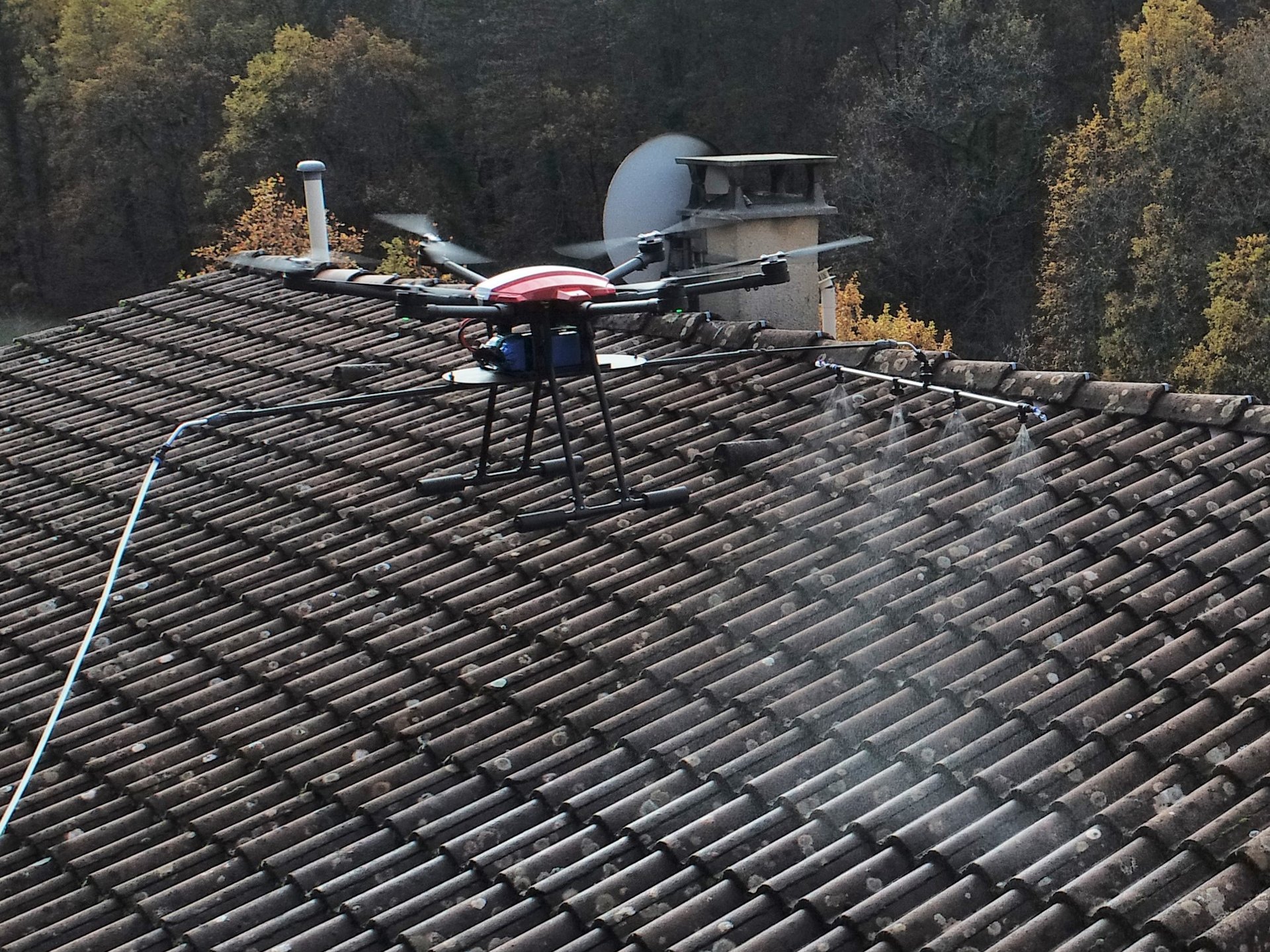 Drone de pulvérisation en vol au-dessus d’une toiture